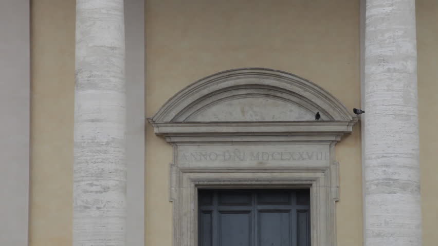Footage of birds perched over arch of a doorway
