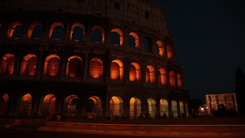 Traffic passes in front of the lit up Roman Colosseum as traffic passes in front