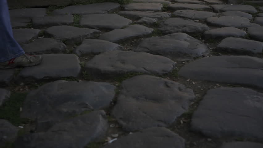 Footage of feet walking across cobblestones in Rome, Italy.