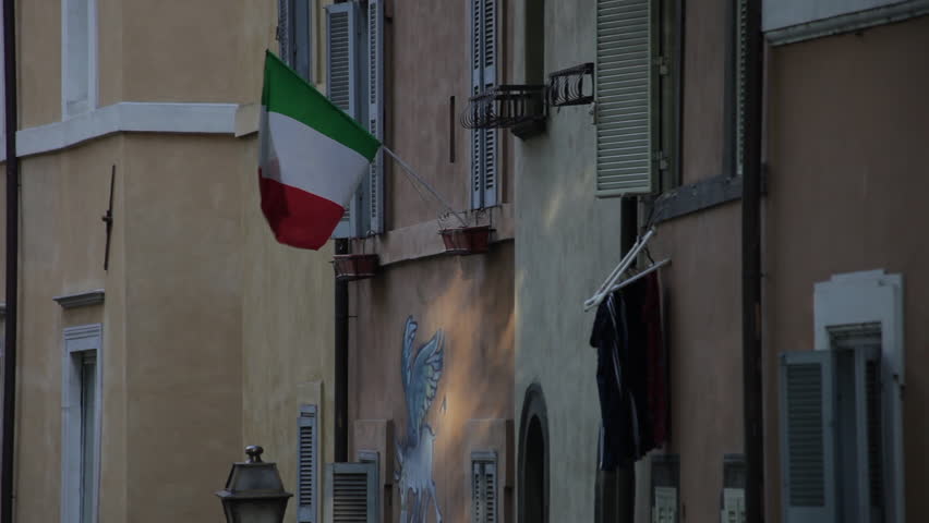 Walls and windows of a quiet Italian street. An Italian flag is prominently