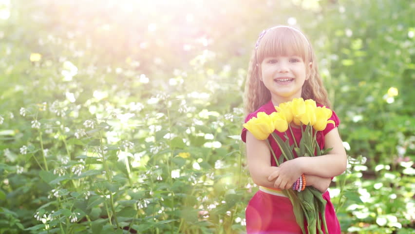 Girl turned to the camera. She is holding a large bouquet of yellow tulips
