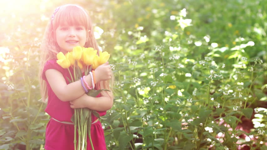 3s girl hugging a bouquet of yellow tulips. Lens flare