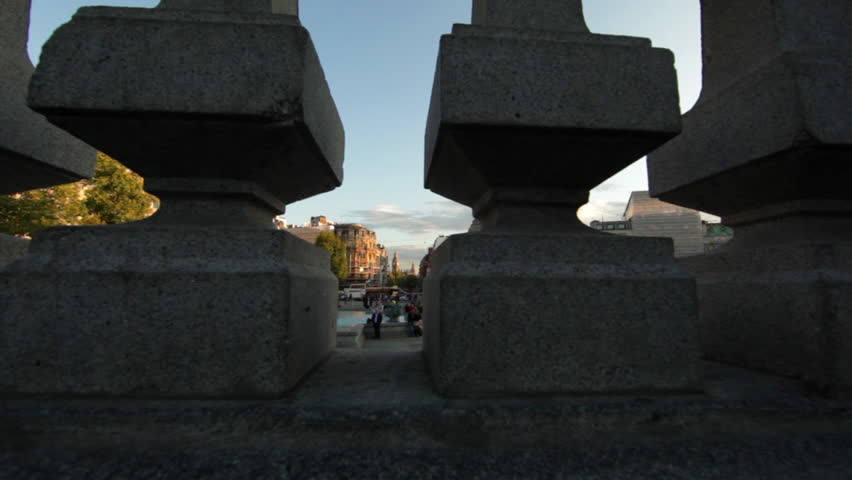 Camera moving from behind small pillars to reveal Trafalgar Square in London.