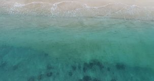 Aerial view waves break on white sand beach, Sea waves on the beautiful beach aerial view drone 4k shot.