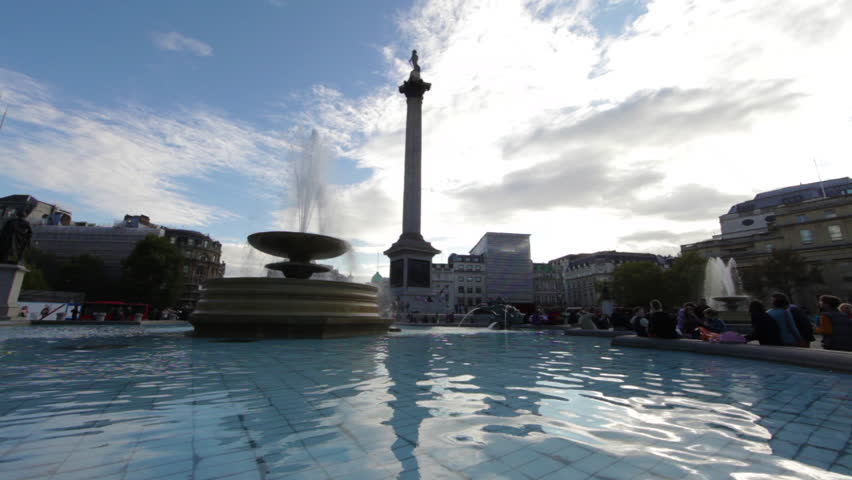 People sitting by a fountain on Trafalgar Square in London. Lord Nelson's