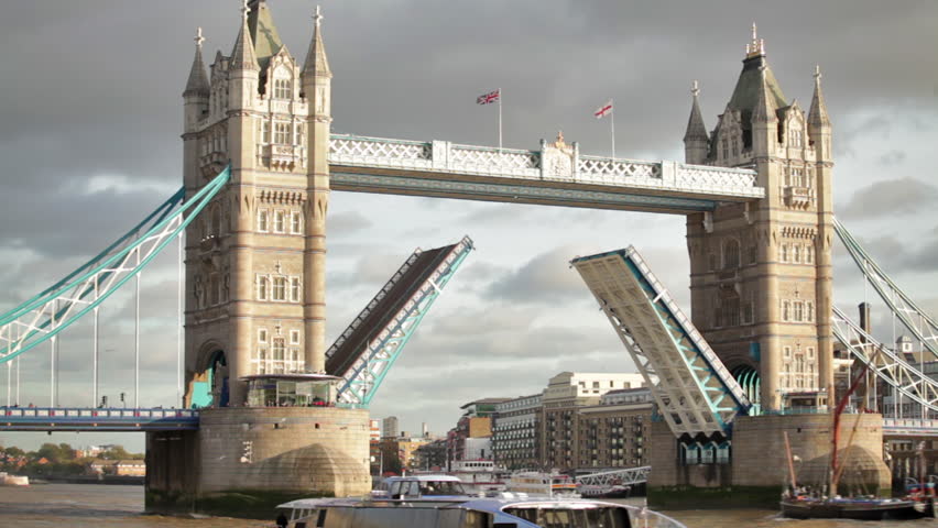 Boat passes through Tower Bridge with bascules raised, other boat in foreground,