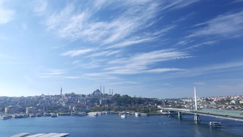 Fatih area panorama from opposite shore of Golden horn, Suleymaniye Mosque dominate over skyline. Halic Metro Bridge seen on right. Nice light clouds across blue sky, morning hour shot of Istanbul