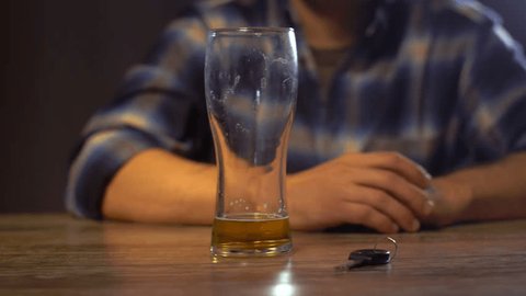 alcohol abuse, drunk driving and people concept - male driver drinking alcoholic beer at home or bar and taking car key from table