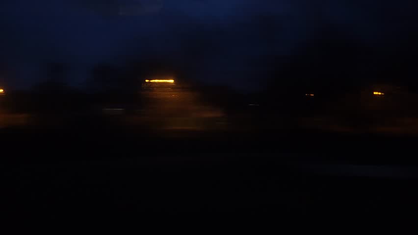 Panorama of the night city is blurred in motion. A view from the window of a train or a car on the night city in motion.
