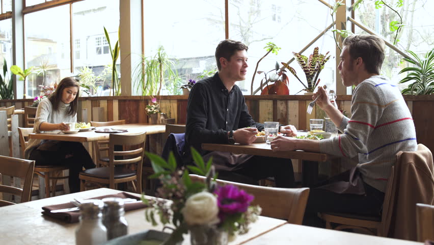 Medium wide shot of two men eating at a restaurant