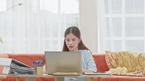 Asian woman is smiling and expressing happy feeling on the computer laptop screen. young female got good news and show  cheerful face.Happiness women looking on laptop read message excited at home
