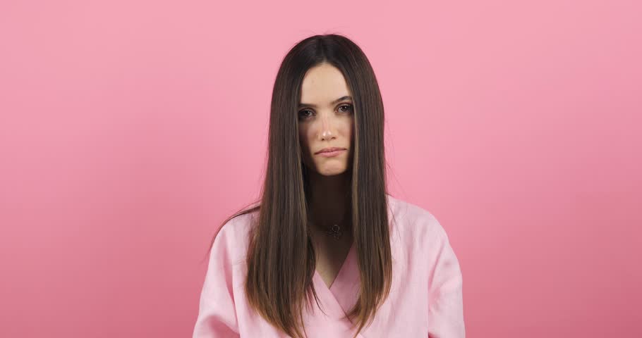 Depressed young woman looking at split brunette hair ends. Worried sad girl feels upset about brittle damaged dry hair loss concept. Female hormone problems concept isolated pink background. Royalty-Free Stock Footage #3385182105
