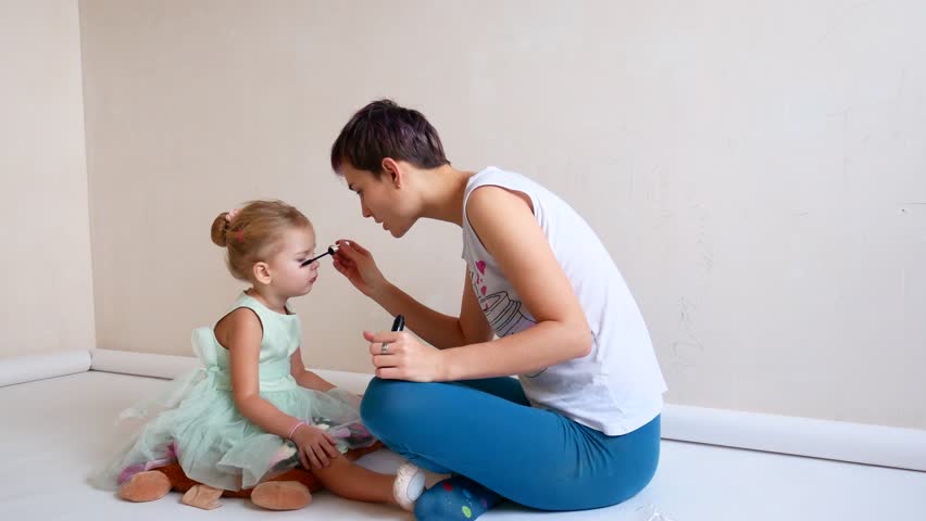 Mother makes up eyes with mascara to the daughter