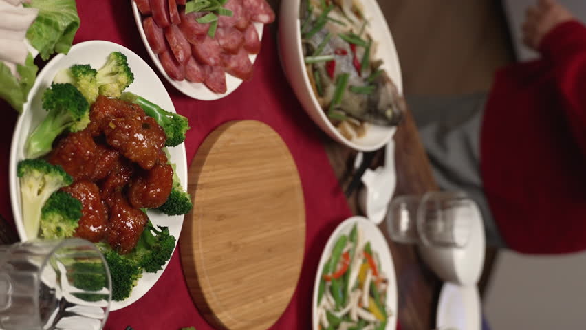 Vertical Screen: asian senior woman grandmother wearing red clothes looking at daughter in law carrying soup, getting ready for family reunion meal at home. word on cabinet translation
