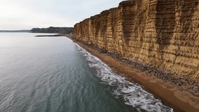 Top cinematic aerial view to the West Bay Cliffs, West Bay, Jurassic Coast, Dorset, England. 4K drone footage. United Kingdom landmarks. Aerial landscape and wild nature