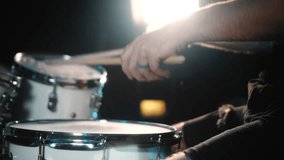The drummer plays drums in a dark studio with lights on the back. Slow motion video.