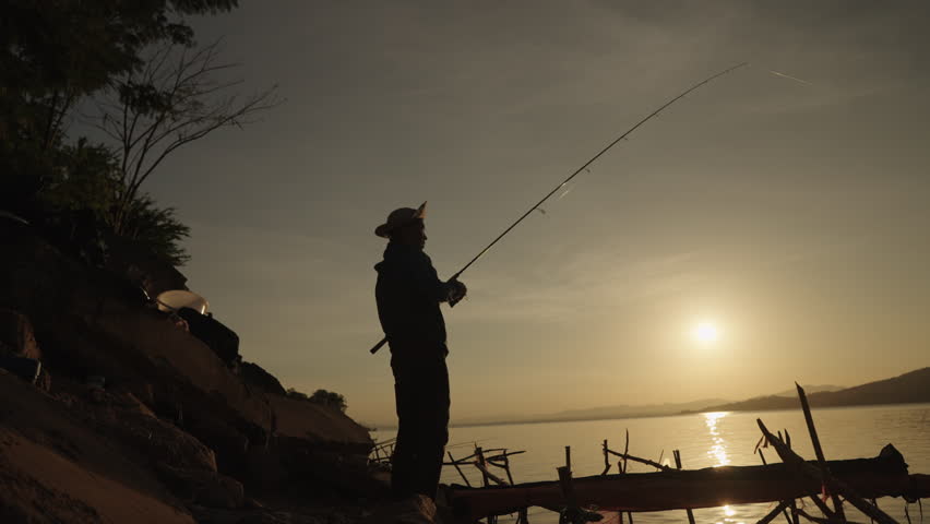 Fishermen are using fishing rods in the reservoir during Silhouette sunset.