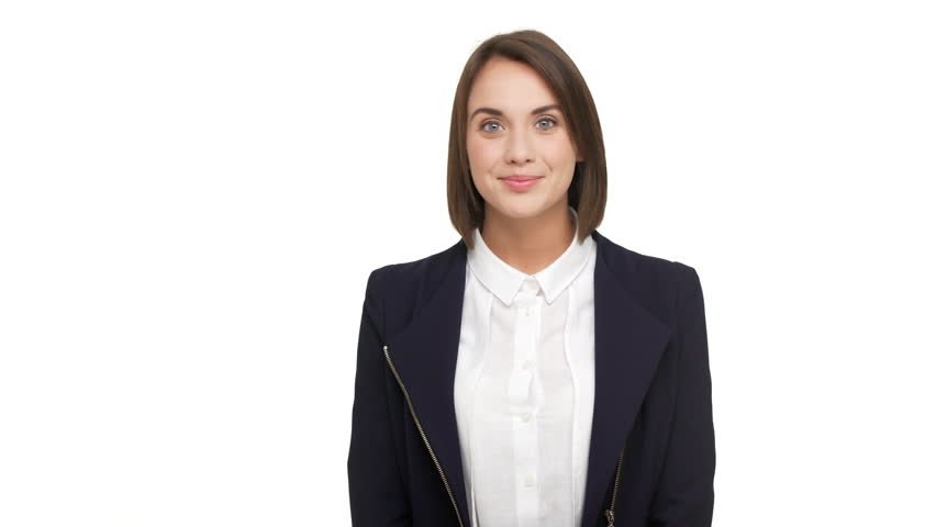 portrait of cute young businesswoman wearing white blouse and black jacket  welcoming with big smile being hospitable waving hand at camera over white background. Concept of emotions