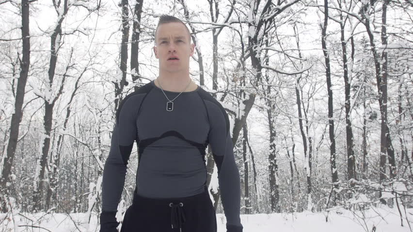Slow Motion Of Young Sportsman Getting Ready To Start Jogging Outdoors In Snow