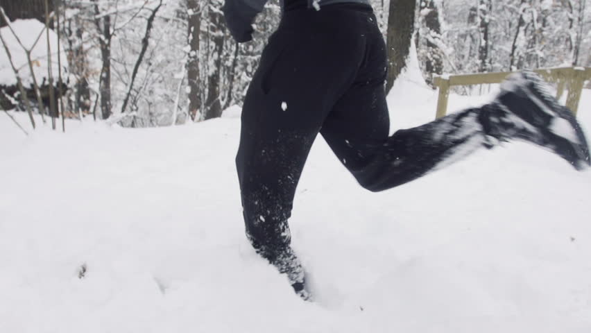 Slow Motion Of Young Sportsman Jogging Outdoors Through Snow