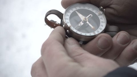 Close up on compass instrument in gloved hand . Mountain hiking trails. Winter mountain trip concept.