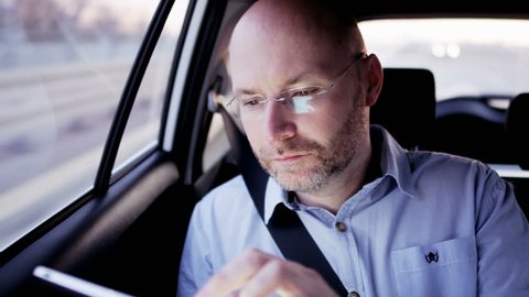 Bald Businessman Wearing Glasses and Using a Tablet