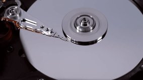 The hdd  working, the head moves over the disk, the texts recorded on this disk are reflected on its surface. Top view. Macro. Closeup
