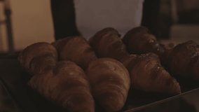 Closeup shot of woman, waiter or baker carry tray full of freshly baked croissants to table. Concept bakery, french cafe or restaurant, smal business entrepreneurship