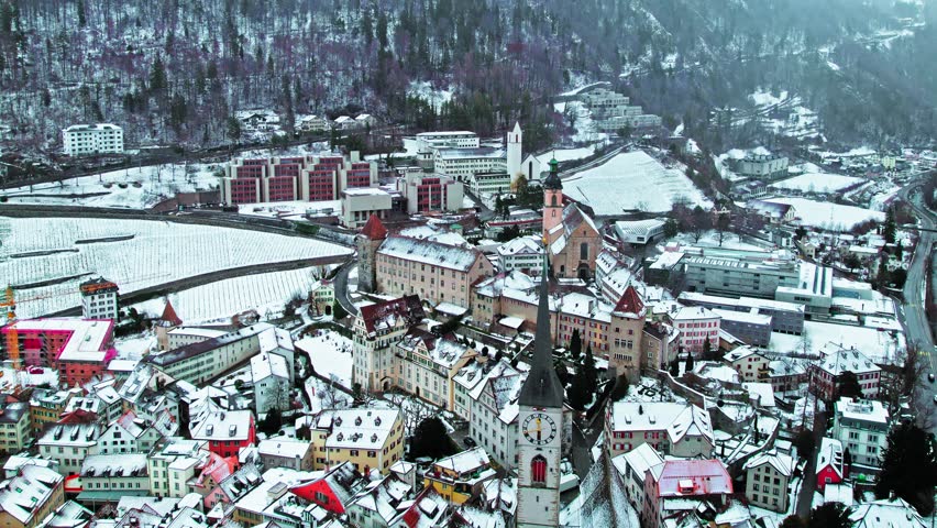Aerial view of Alpine City Chur with a tower clock and colourful houses. The capital of the Graubünden canton covered with snow in eastern Switzerland. 