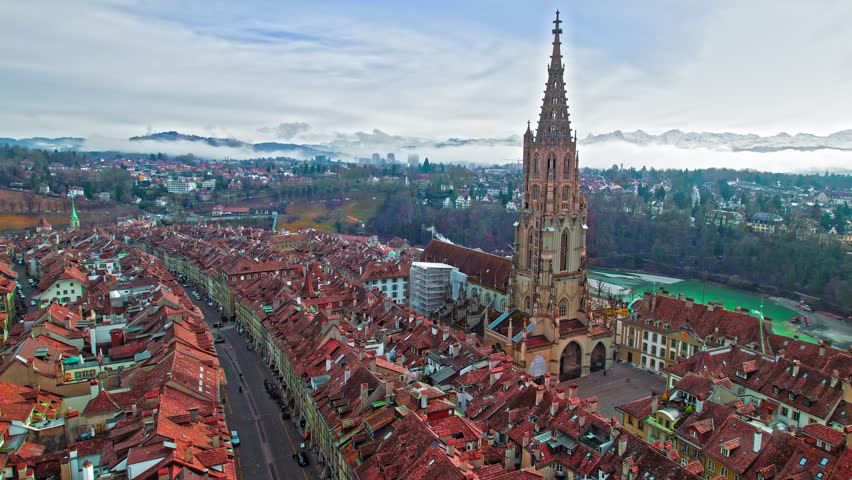 Aerial view of Aare River and Berner Münster Cathedral in Old Town of Bern, Switzerland. Panoramic view of red rooftop houses of medieval townscape, Gothic architecture in Europe.
