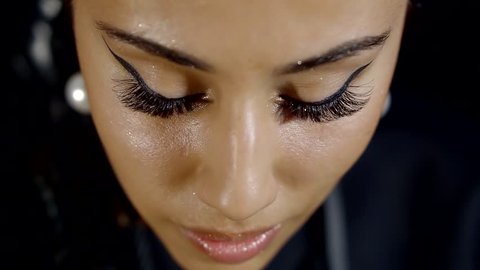 a close shot at the woman's face, the lady raises her eyes with long false eyelashes