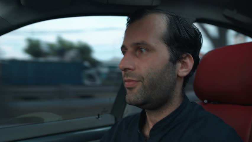 Close-up of calm handsome caucasian man driving his car in the evening