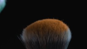 Macro detail of cosmetic brushes clashing each other in super slow-motion at 1000 fps with orange and green powder flying in the air