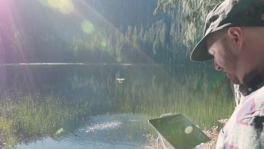 Drone Pilot Flying Over Forest Lake in Nature with Sun Lens Flare