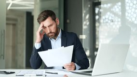 Confused puzzled businessman in a formal suit having difficulty with paper work sitting at workplace in business office. Frustrated financier reviewing documents, unhappy with bad financial results - Powered by Shutterstock - Get 15% off with code: PIKWIZARD15