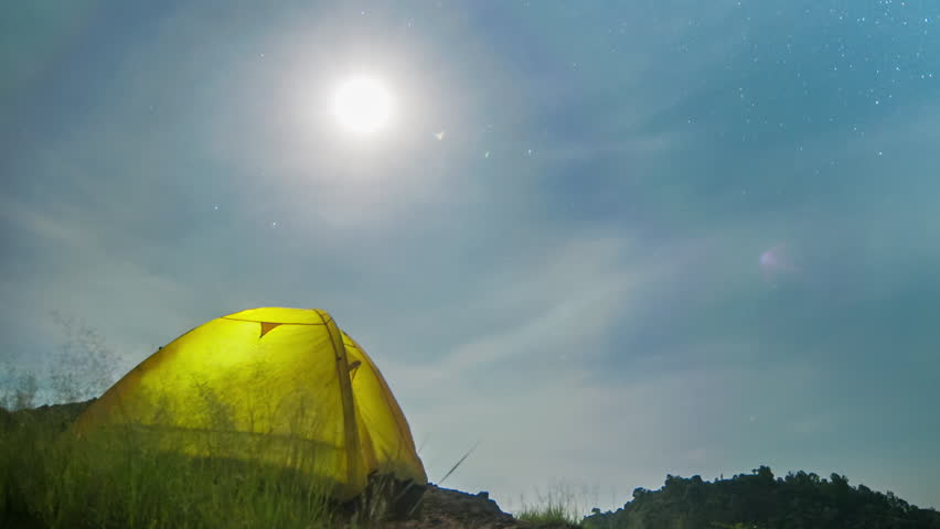 4k Timelapse Camping tent with lights on inside under starry sky and hello moon rising over high mountains, night landscape