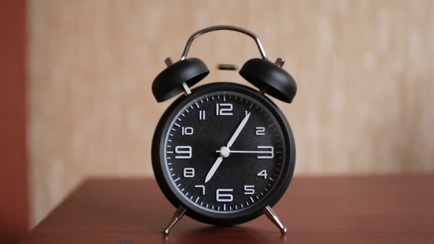 Old fashioned alarm clock ringing early in the morning. The woman