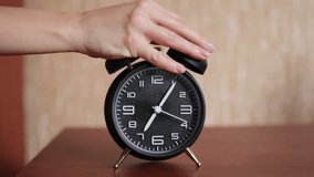 Old fashioned alarm clock ringing early in the morning. The woman's hand stops the alarm clock to sleep longer. - Powered by Shutterstock - Get 15% off with code: PIKWIZARD15