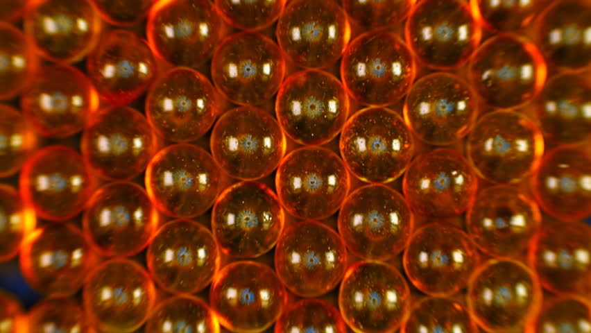 Broun-red transparent capsules of fish oil are lined up in a row. Macro. Closeup. Dolly shot. Bottom view