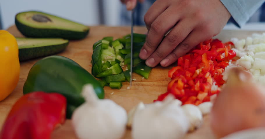 Cooking, healthy food and hands with knife in a kitchen with vegetables, avocado and health meal prep. Person, diet and lunch in a home with salad, cutting wood board and chop for dinner in a house