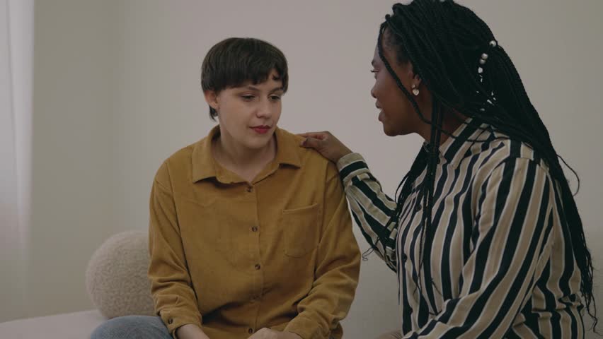 Loving caring beautiful black female talking to upset depressed young friend, caring girl giving support advise understanding empathy to stressed adult caucasian woman. Serious conversation Royalty-Free Stock Footage #3390414789