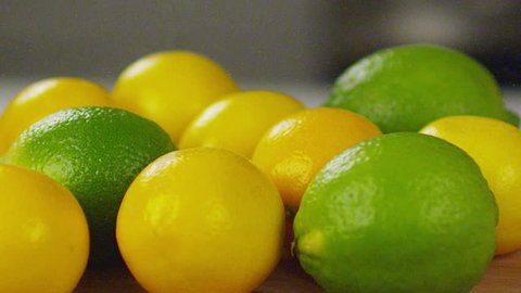 A medium dolly shot of lemons and limes sitting on a lightly-colored wooden cutting board. Panning back and forth. Filmed on a RED Epic. Stockvideo