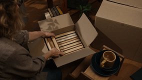 Preparing for move, relocation. Young woman packing books in carton box at home.  - Powered by Shutterstock - Get 15% off with code: PIKWIZARD15