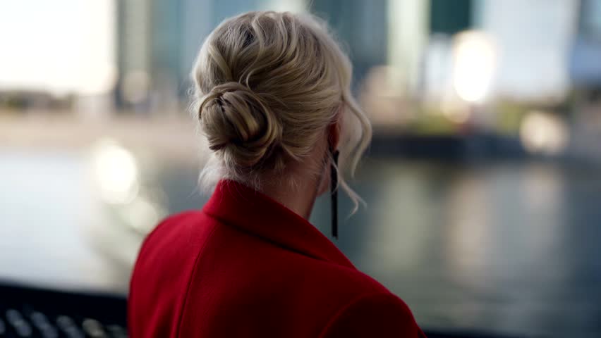 alluring young adult woman admiring river standing alone on city embankment, rear view