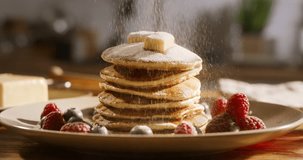 Sprinkling sugar powder on tasty pancake, slow motion. No people, advertising, cinematic. Excess sugar and diabetes, tasty but safe and delicious gluten-free options. Guilt-free cheat meal, wellness