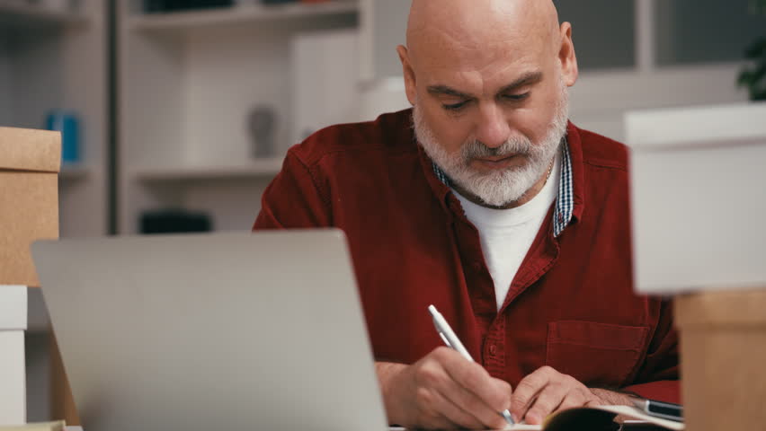 Middle-aged small business owner keeping sale records, writing down expenses