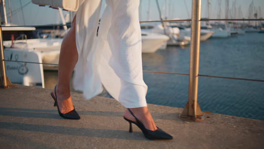 Woman feet walking waterfront summer weekend close up. Unrecognizable girl in black high-heels strolling at beautiful sunny embankment. Trendy young lady legs stepping on asphalt pier at windy evening Royalty-Free Stock Footage #3390827425
