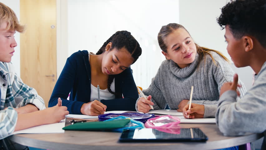Group of secondary or high school students sitting around table collaborating in study area - shot in slow motion - Powered by Shutterstock - Get 15% off with code: PIKWIZARD15