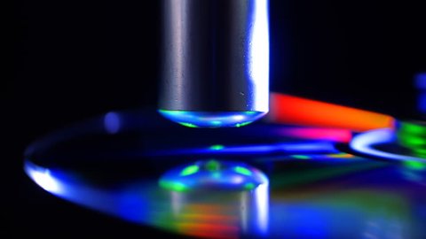 The green laser beam slides over the surface of the compact disk and reads the data on black background. The laser quickly finds the right sectors and take off information. Colorful reflections