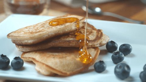 maple syrup being poured over pancakes